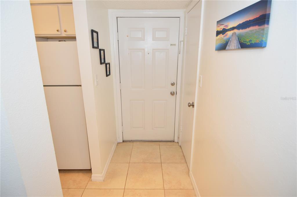 An entryway features a white front door, tiled flooring, and an adjacent white refrigerator — 8625 MALLARD RESERVE DRIVE UNIT 101, TAMPA, FL