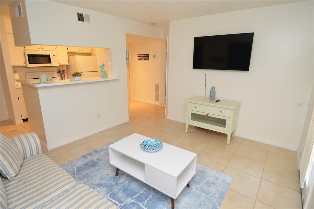 A living room with tile floors, a white coffee table, and a wall-mounted television — 8625 MALLARD RESERVE DRIVE UNIT 101, TAMPA, FL