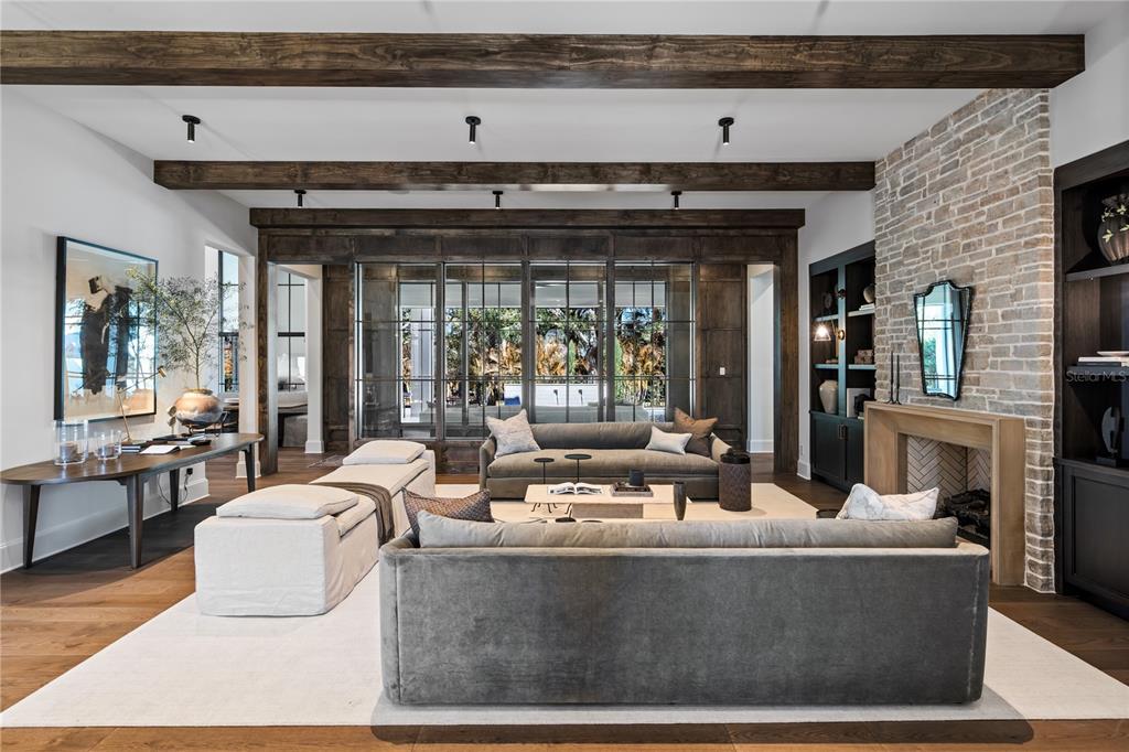 A living room features wood ceiling beams, a brick fireplace, and large glass-paned doors — 9323 GLADYS GARDEN COURT, WINDERMERE, FL