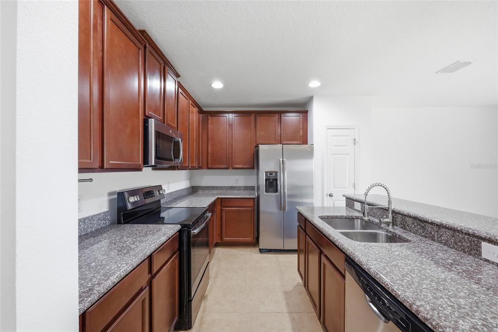 A kitchen features dark wood cabinets, granite countertops, stainless steel appliances, and a breakfast bar — 196 PRIMROSE DRIVE, DAVENPORT, FL