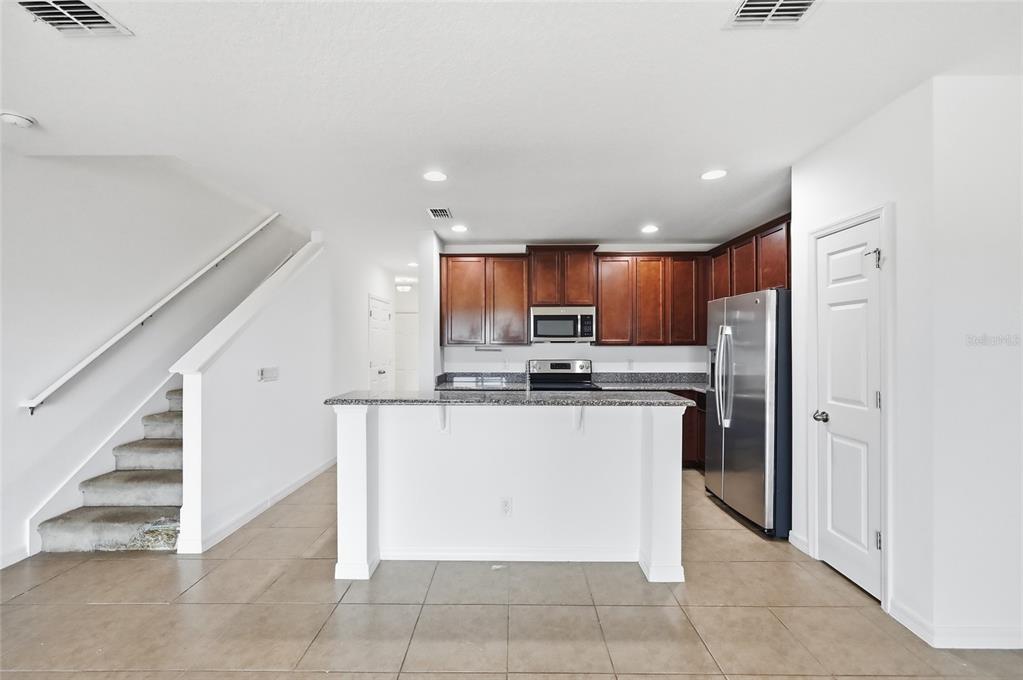 A kitchen with dark wood cabinets, granite countertops, stainless steel appliances, and an island — 196 PRIMROSE DRIVE, DAVENPORT, FL