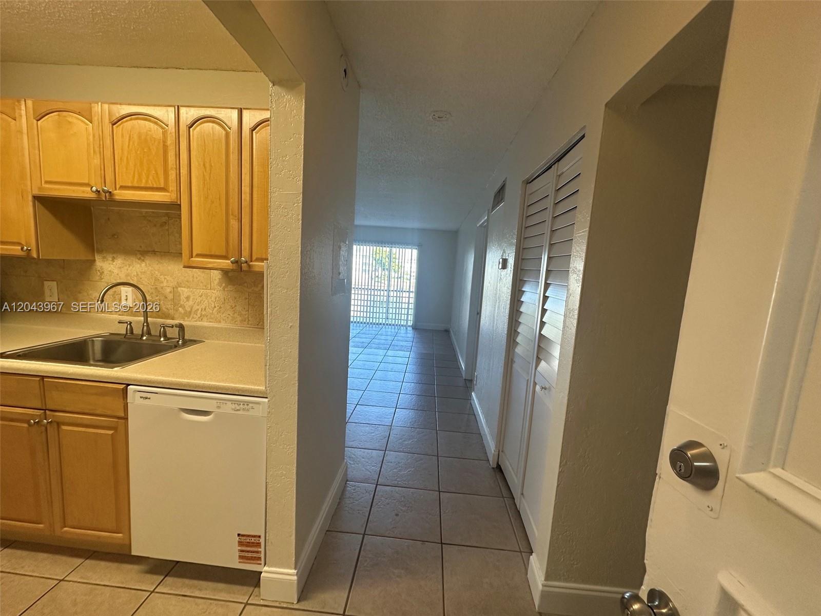 A kitchen with light wood cabinets and a dishwasher opens into a tiled hallway — 2775 Taft St # 307, Hollywood FL 33020, HOLLYWOOD, FL