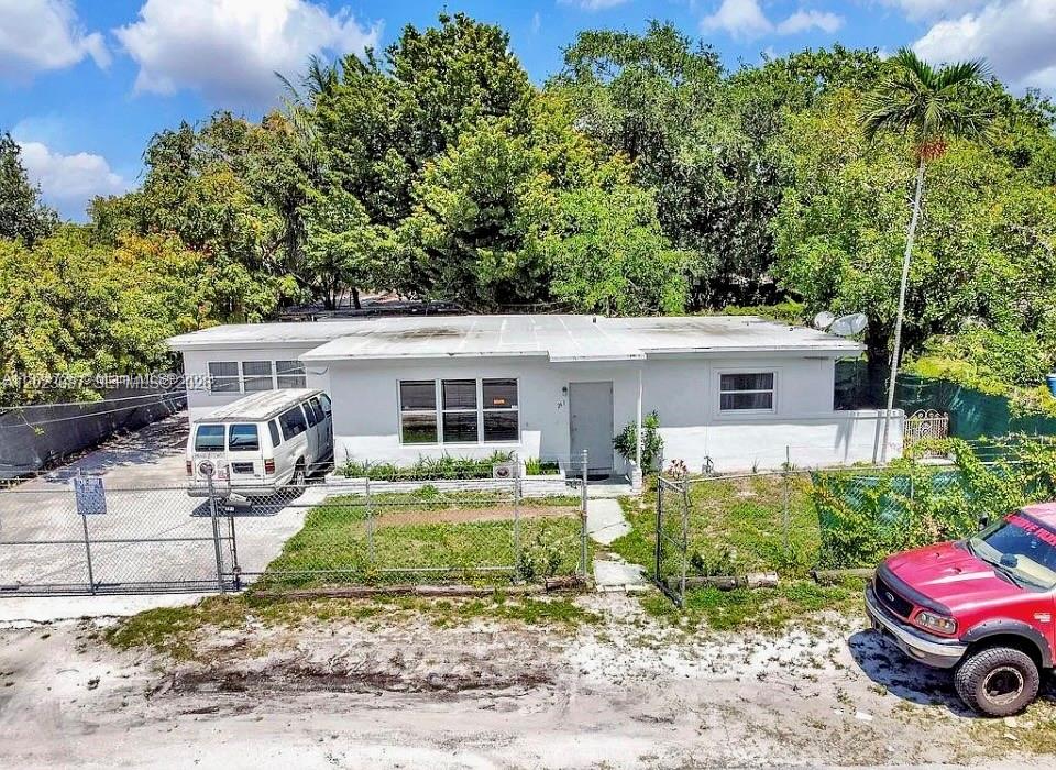 A single-story white house with a flat roof sits behind a chain-link fence — 261 NW 73rd Ter, Miami FL 33150, MIAMI, FL