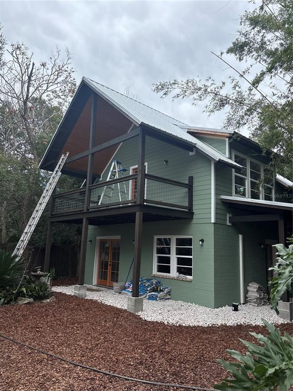 A two-story house with green siding, a metal roof, and a second-story balcony — 1027 NW 11TH AVENUE, GAINESVILLE, FL
