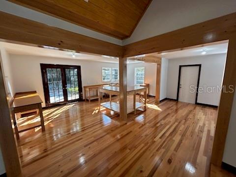 An open-concept room features polished hardwood floors, exposed wooden ceiling beams, and a central island — 1027 NW 11TH AVENUE, GAINESVILLE, FL