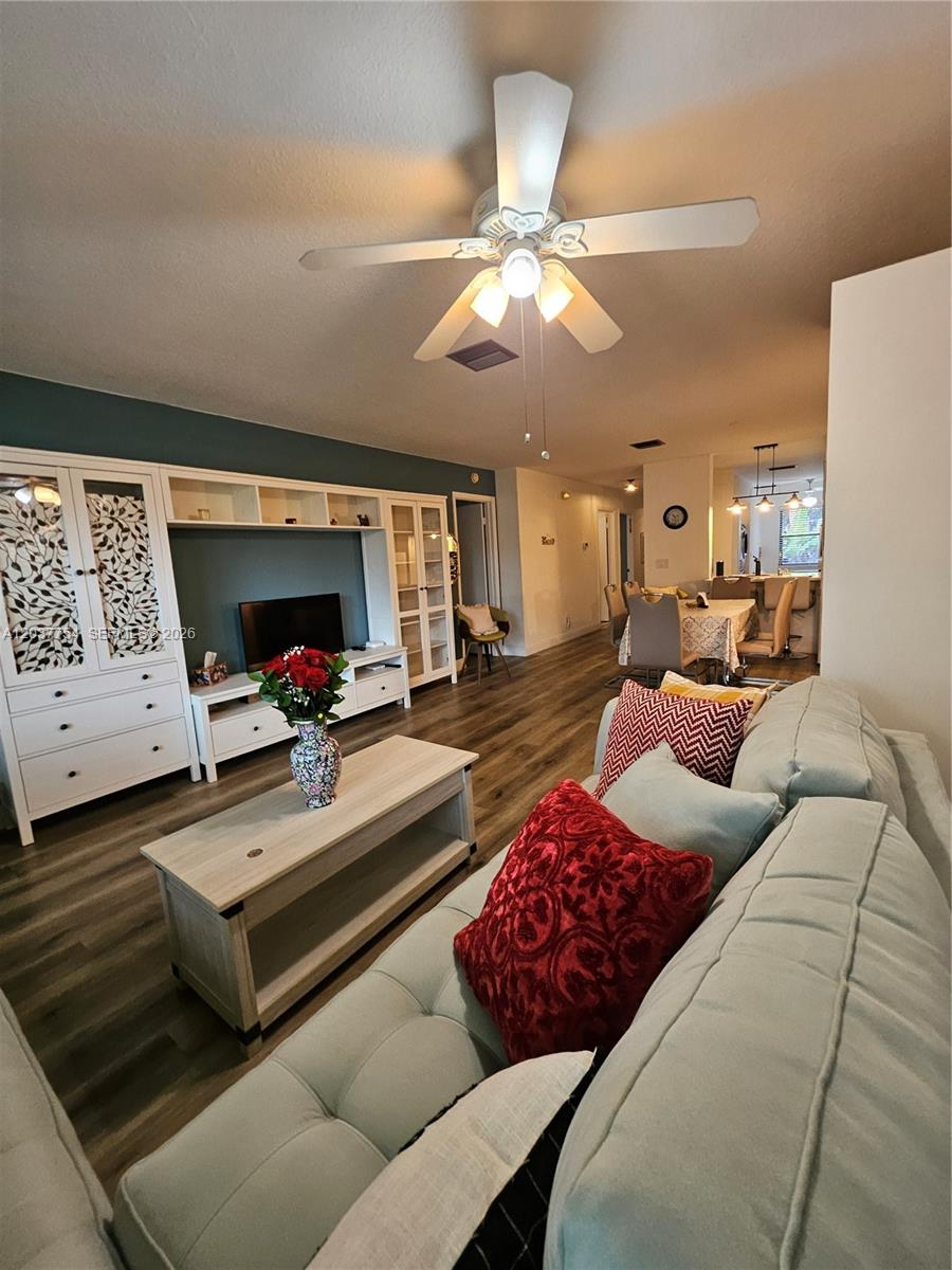A living room features a light blue sofa, a white entertainment center, and wood-look flooring — 3015 SW 21st Ter # 371B, Delray Beach FL 33445, DELRAY BEACH, FL