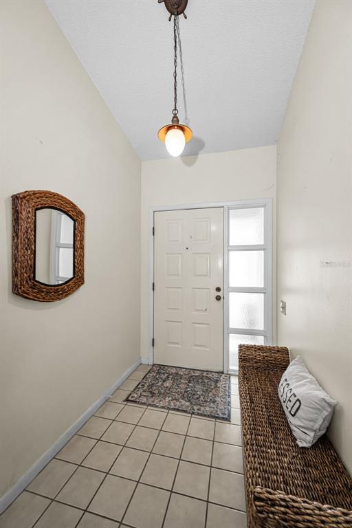 An entryway features a tiled floor, a wicker bench, a wall mirror, and a pendant light — 3114 SUMMERVALE DRIVE, HOLIDAY, FL
