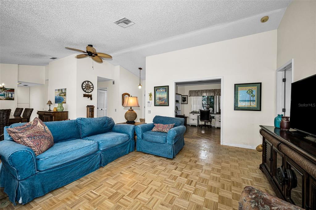 A living room features a blue sofa, a matching armchair, and parquet wood flooring — 3114 SUMMERVALE DRIVE, HOLIDAY, FL