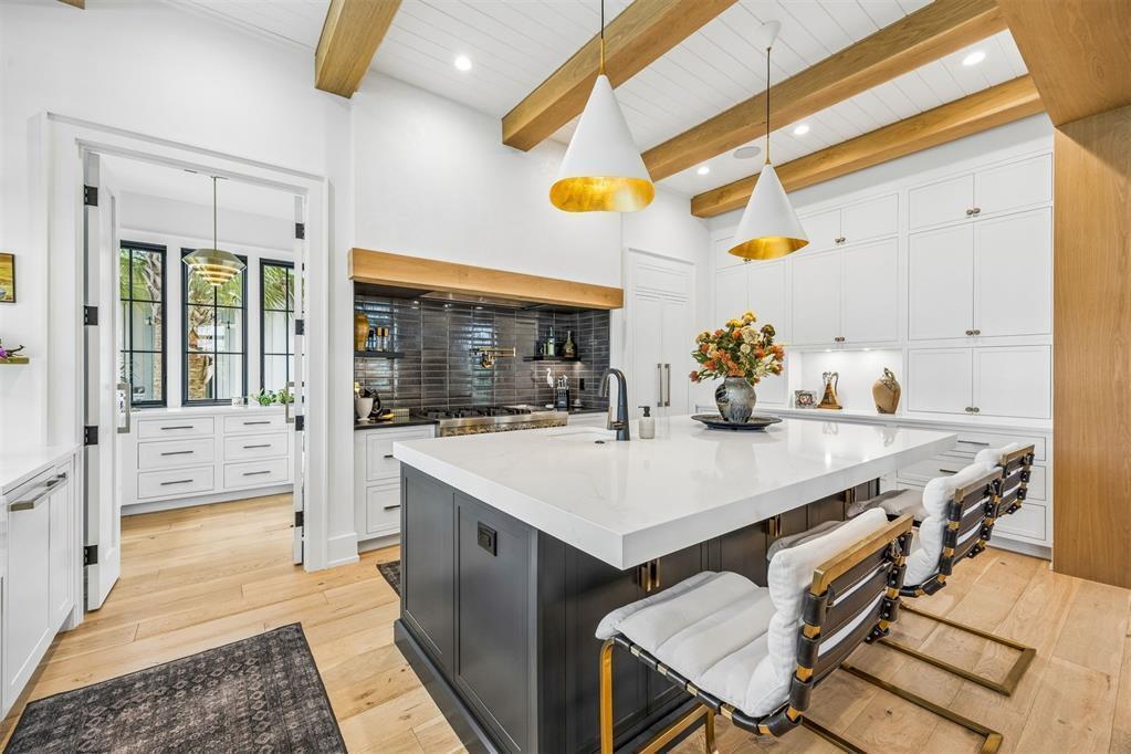 A modern kitchen features a dark island with white countertops, wooden ceiling beams, and white cabinetry — 52 Wallan Court, FL 32034, FL