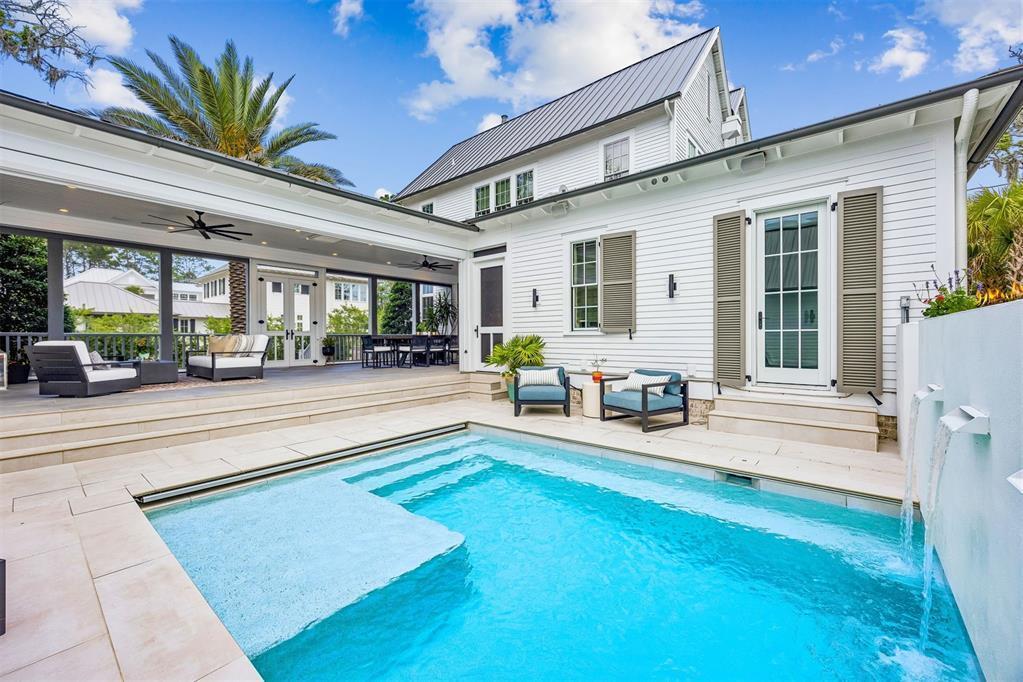 A white house with a covered patio overlooks a small swimming pool with water features — 52 Wallan Court, FL 32034, FL