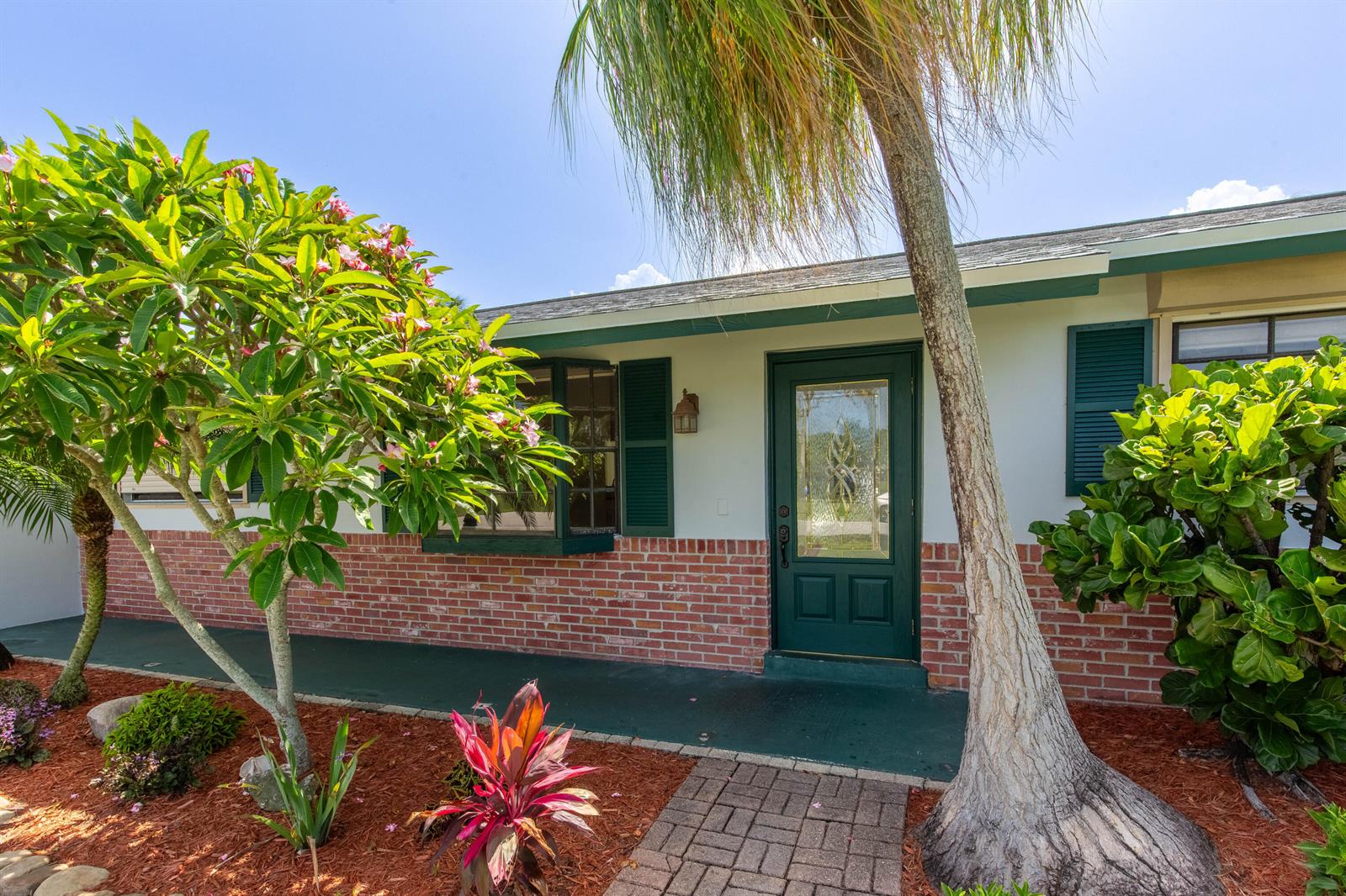 A house exterior features a brick base, white walls, a green door, and tropical landscaping — 12069 Easterly Avenue, Palm Beach Gardens FL 33410, PALM BEACH GARDENS, FL