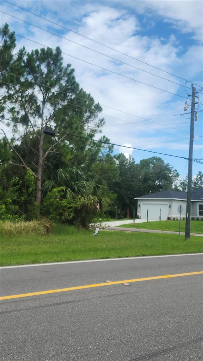 A view of a grassy lot next to a house with a white garage — 202 Haines Road, Palm Bay FL 32908, PALM BAY, FL