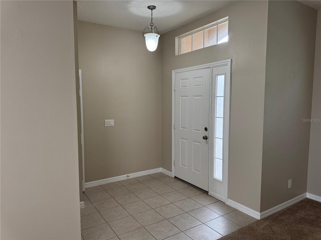 An entryway features tiled flooring, a white front door with a sidelight, and a pendant light — 5004 ADAIR OAK DRIVE, ORLANDO, FL