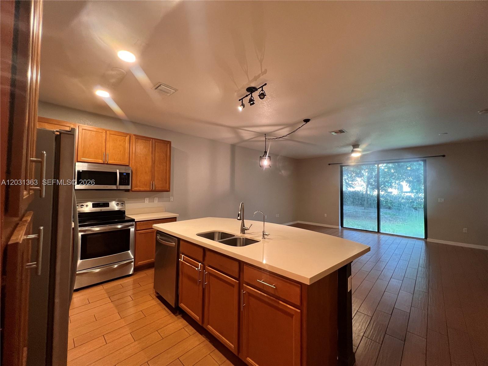 A kitchen with wood cabinets, stainless steel appliances, and a central island with a sink — 4764 E Station Sq, Davie FL 33314, DAVIE, FL