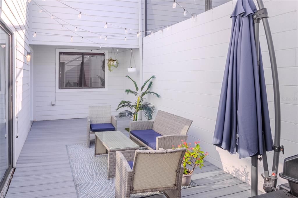 A patio features gray wicker furniture, a patterned rug, string lights, and a large umbrella — 3063 NW 28TH CIRCLE, GAINESVILLE, FL