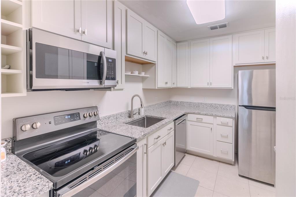 A kitchen features white cabinets, stainless steel appliances, and speckled granite countertops — 3063 NW 28TH CIRCLE, GAINESVILLE, FL