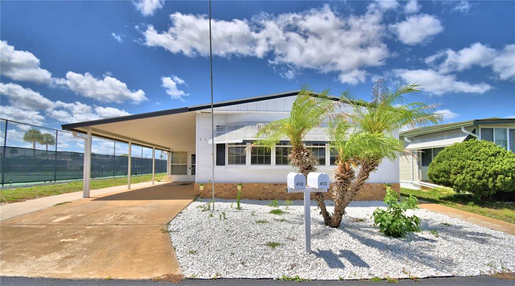 A white manufactured home features a carport, a palm tree, and two mailboxes in front — 4132 SPRUCEWOOD STREET, WINTER HAVEN, FL