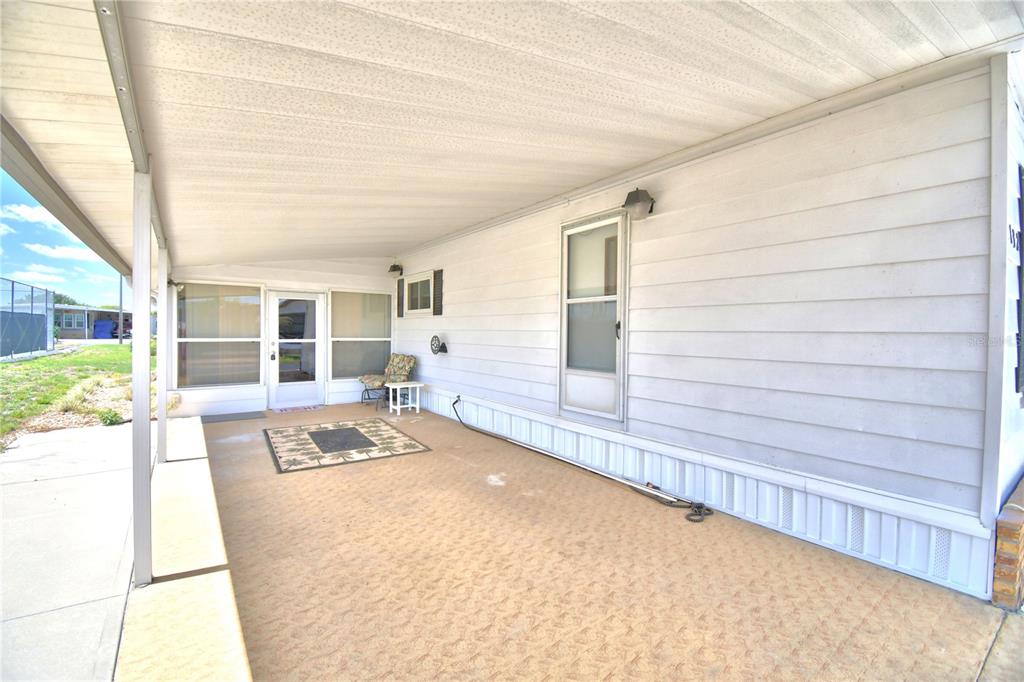 A covered patio with light-colored siding, a concrete floor, and a glass-paneled entry door — 4132 SPRUCEWOOD STREET, WINTER HAVEN, FL