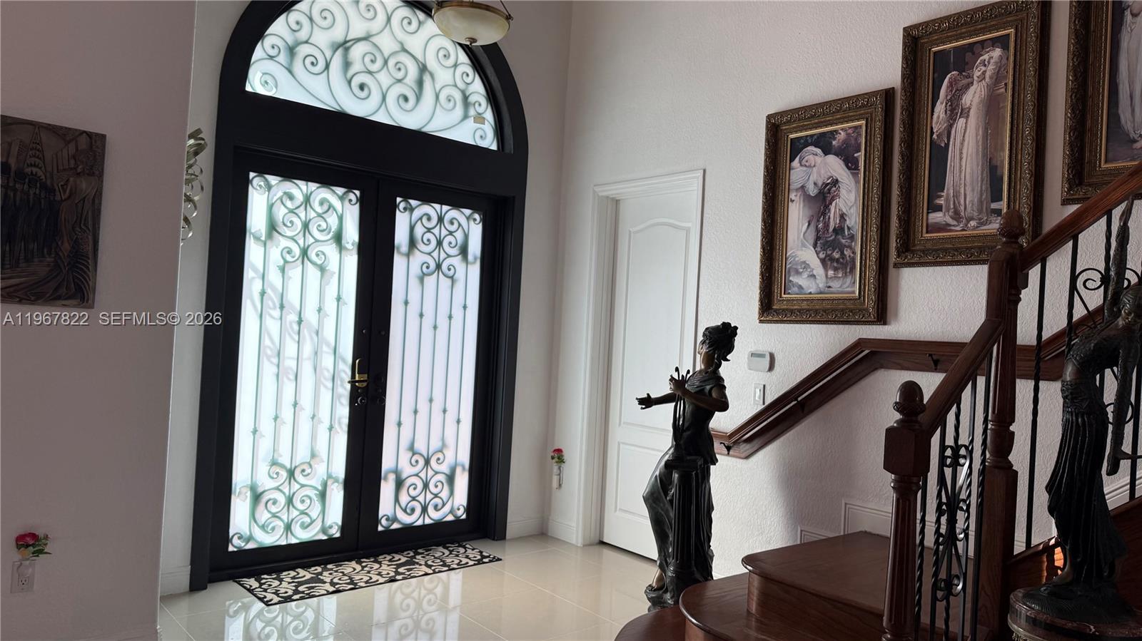 An entryway features a double door with decorative ironwork, a staircase, and framed wall art — 14431 SW 22nd Ter, Miami FL 33175, MIAMI, FL