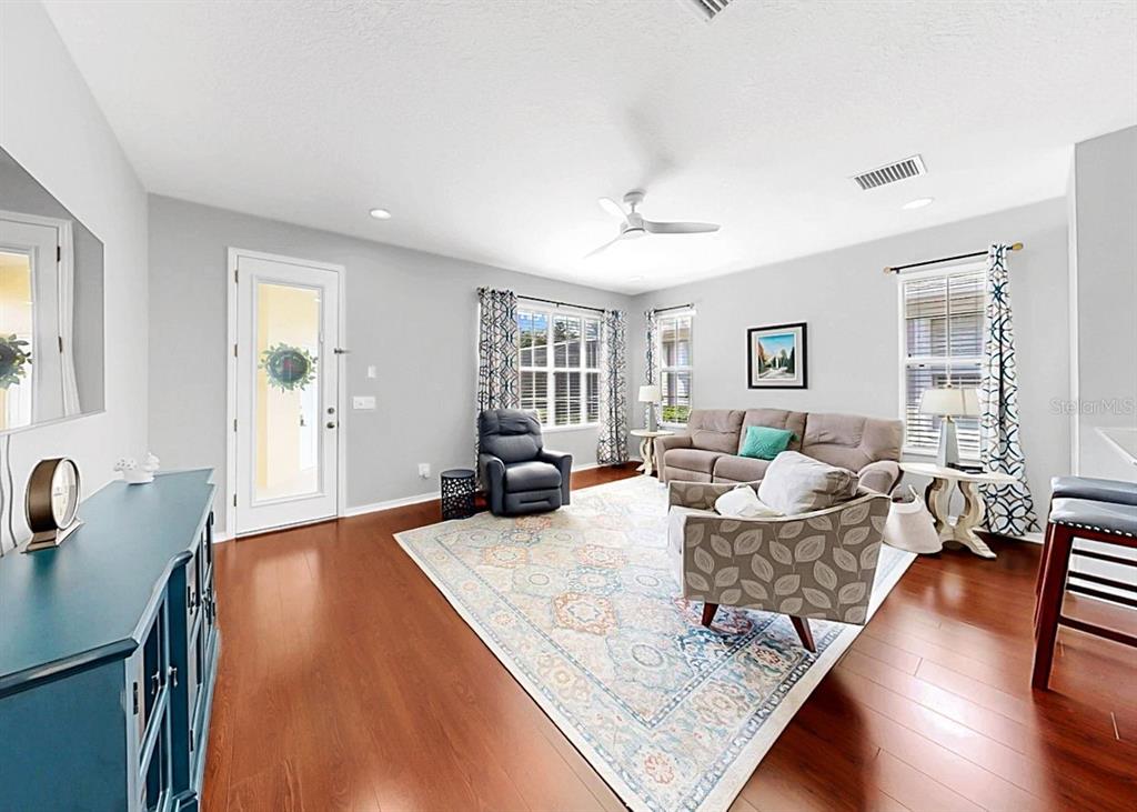 A living room features hardwood floors, a patterned area rug, and neutral-colored furniture — 203 OCEANIA COURT, APOLLO BEACH, FL