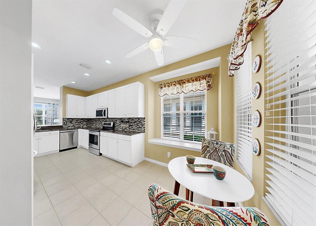 A kitchen with white cabinets, stainless steel appliances, and a small dining area — 203 OCEANIA COURT, APOLLO BEACH, FL