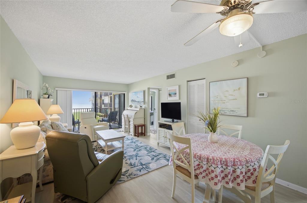 A living and dining area with light green walls, a ceiling fan, and balcony access — 6322 PALMA DEL MAR BOULEVARD S UNIT 216, ST PETERSBURG, FL