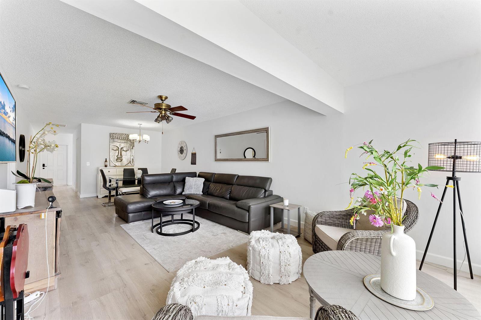 A living room features a dark leather sectional, light wood flooring, and a dining area — 1110 Boxwood Drive # 202, Delray Beach FL 33445, DELRAY BEACH, FL