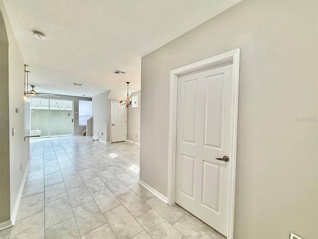 A tiled hallway leads to an open living area with a sliding glass door — 10653 MARSHA DRIVE, NEW PORT RICHEY, FL