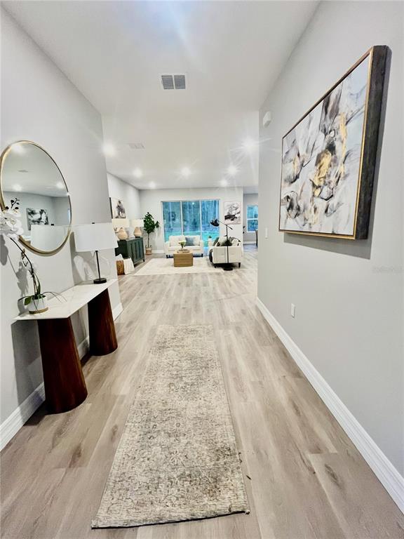 A bright entryway with light wood flooring leads into an open-concept living room — 7 LOBELIA COURT, HOMOSASSA, FL