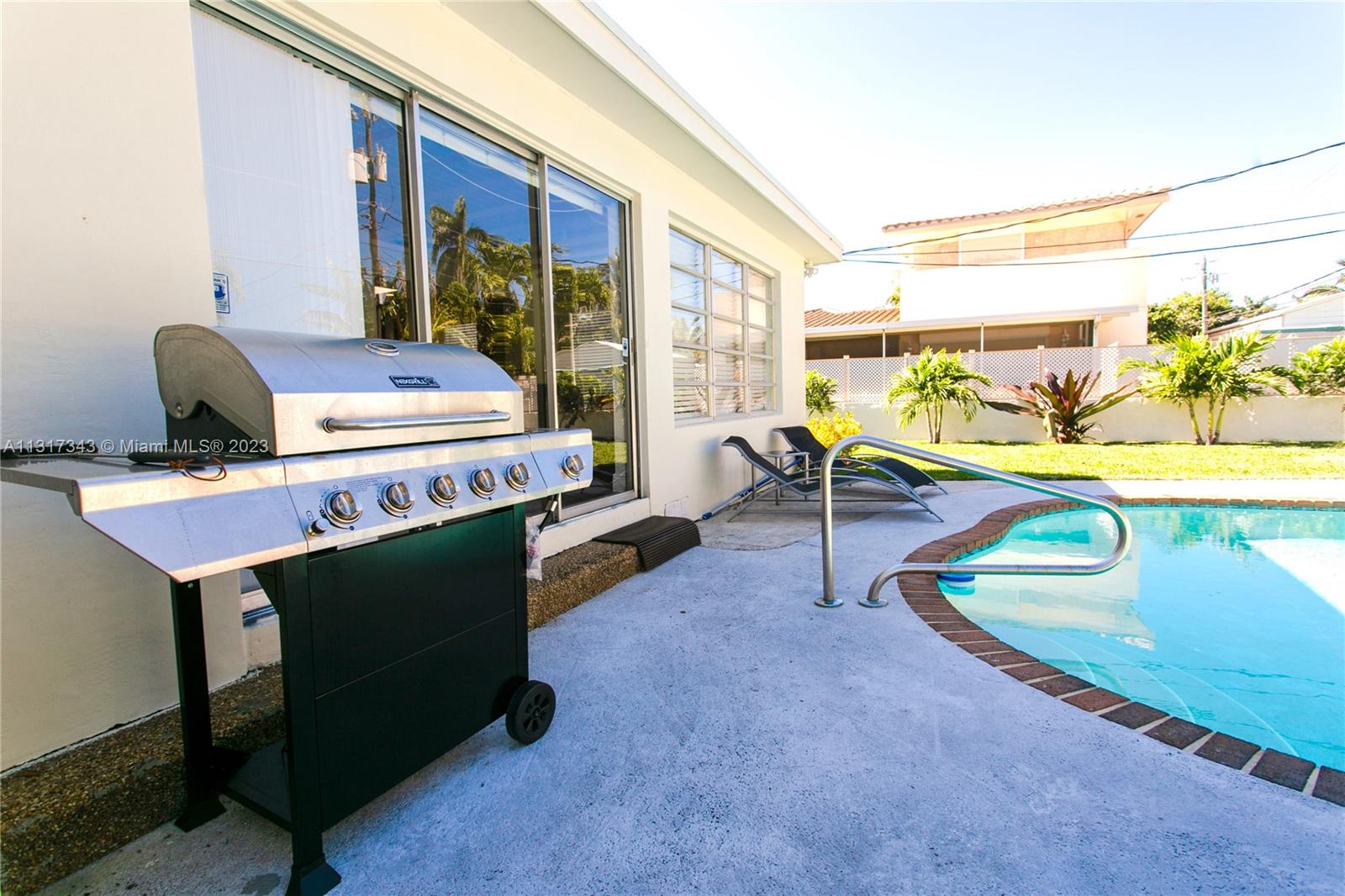 A stainless steel grill sits on a concrete patio beside a swimming pool and house — 951 Washington St, Hollywood FL 33019, HOLLYWOOD, FL