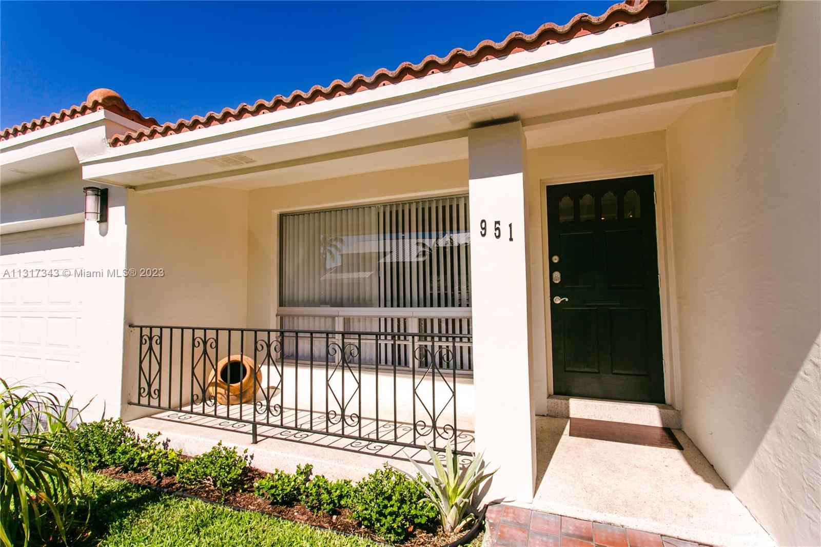 The exterior of a house features a dark front door, a window, and a metal railing — 951 Washington St, Hollywood FL 33019, HOLLYWOOD, FL