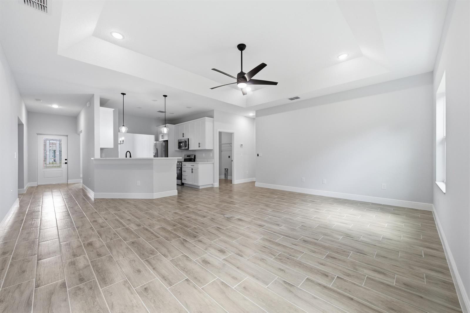 An open-concept living area features a kitchen with white cabinetry and light wood-look tile flooring — 8780 92nd Avenue, Vero Beach FL 32967, VERO BEACH, FL