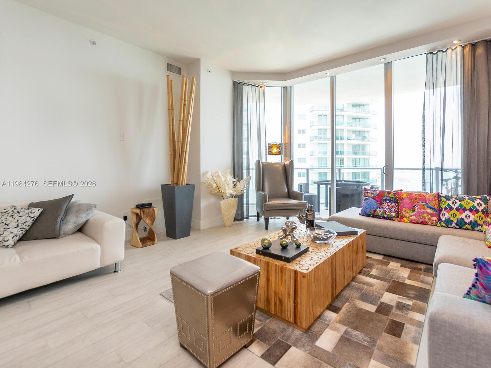 A modern living room features a wooden coffee table, gray seating, and floor-to-ceiling windows — 1300 Brickell Bay Dr # 3804, Miami FL 33131, MIAMI, FL