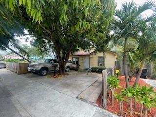A single-story house with a concrete driveway, a large tree, and a parked silver SUV — 1416 N 2nd Ave N, Lake Worth FL 33460, LAKE WORTH, FL