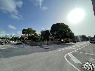 A street-level view shows a fenced corner lot with mature trees under a bright sun — 1416 N 2nd Ave N, Lake Worth FL 33460, LAKE WORTH, FL