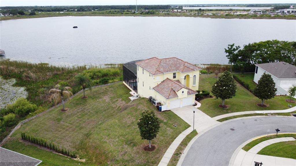 An aerial view shows a yellow two-story house with a pool cage beside a lake — 350 CHEROKEE AVE, HAINES CITY, FL