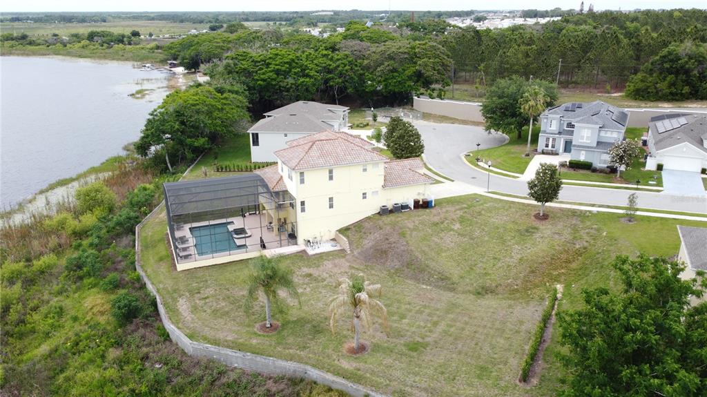 An aerial view shows a yellow two-story house with a screened pool near a lake — 350 CHEROKEE AVE, HAINES CITY, FL