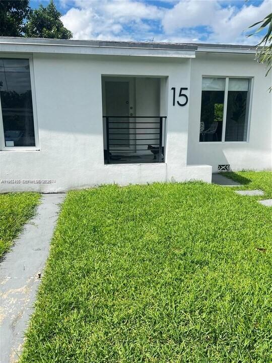 The exterior of a white house features a front entrance with a black metal railing — 15 NW 52nd St, Miami FL 33127, MIAMI, FL