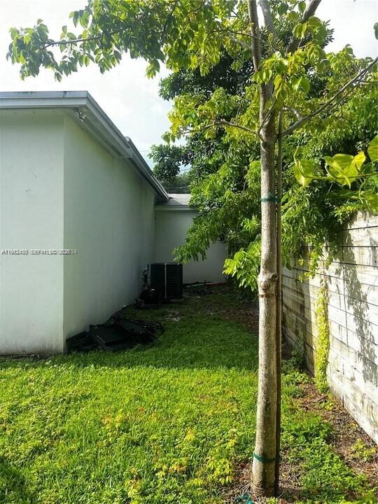 A side view of a white house exterior with a tree and an outdoor AC unit — 15 NW 52nd St, Miami FL 33127, MIAMI, FL