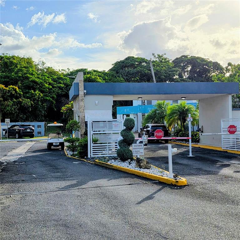 A gated entrance with a security booth, a golf cart, and two cars parked inside — 512 CALLE BROMELIA, CAROLINA, PR