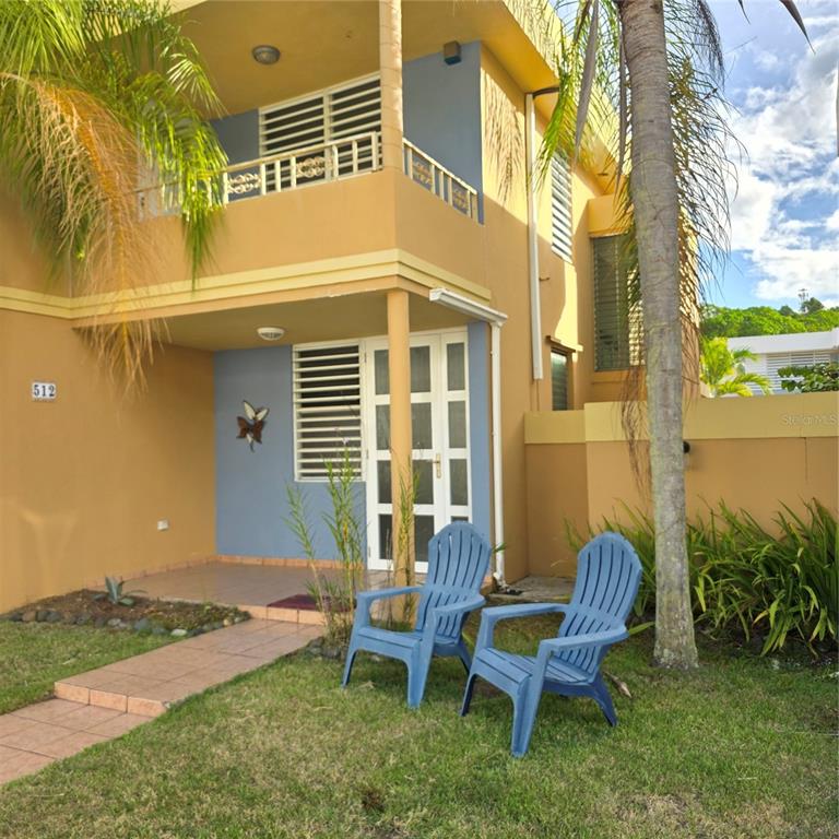 A two-story tan building with a blue accent wall, a front patio, and two chairs — 512 CALLE BROMELIA, CAROLINA, PR