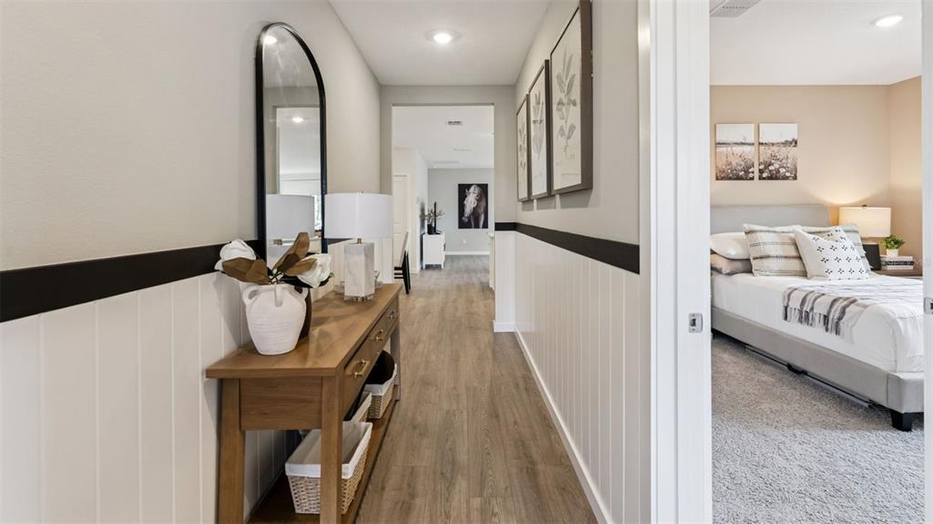 A hallway with wood-look flooring and wainscoting leads to a bedroom with a bed — 2928 ELIO HAMMOCK DRIVE, ST CLOUD, FL