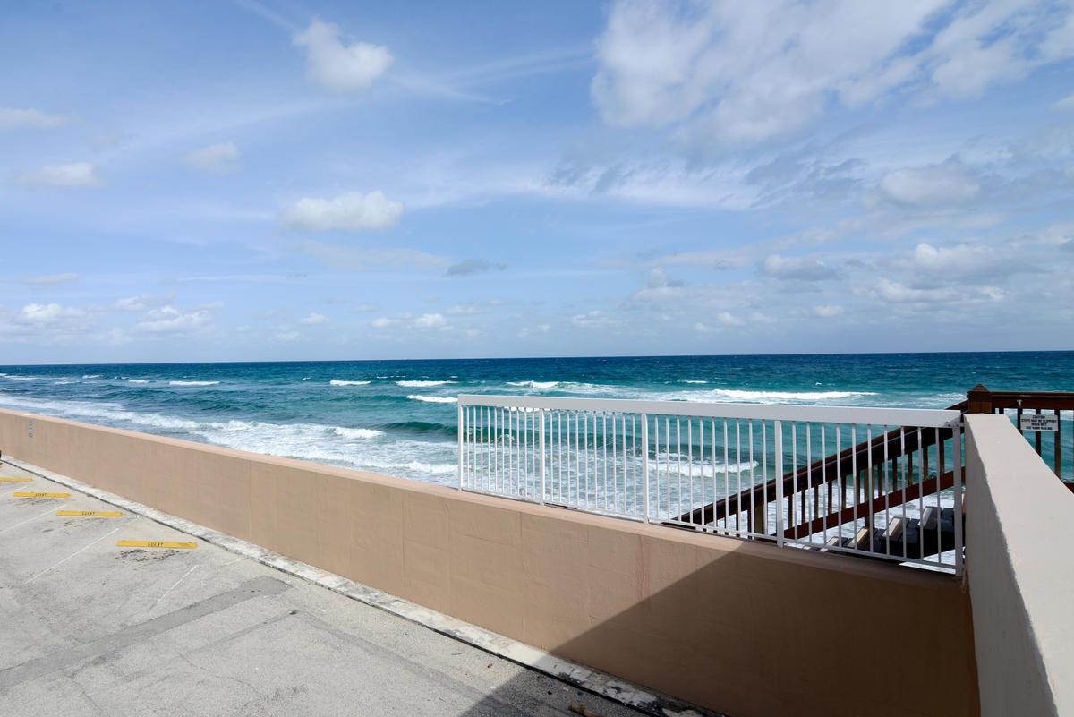 An outdoor parking area overlooks the ocean with a white railing and wooden stairs — 3450 S Ocean Boulevard # 508, Palm Beach FL 33480, PALM BEACH, FL