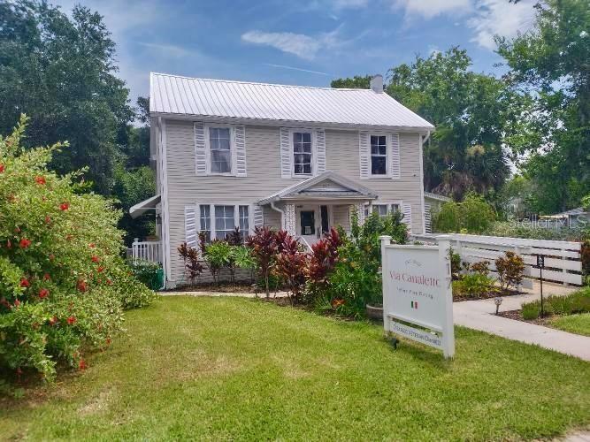 A two-story light-colored house with a metal roof and a restaurant sign in the yard — 317 N ORANGE STREET, NEW SMYRNA BEACH, FL