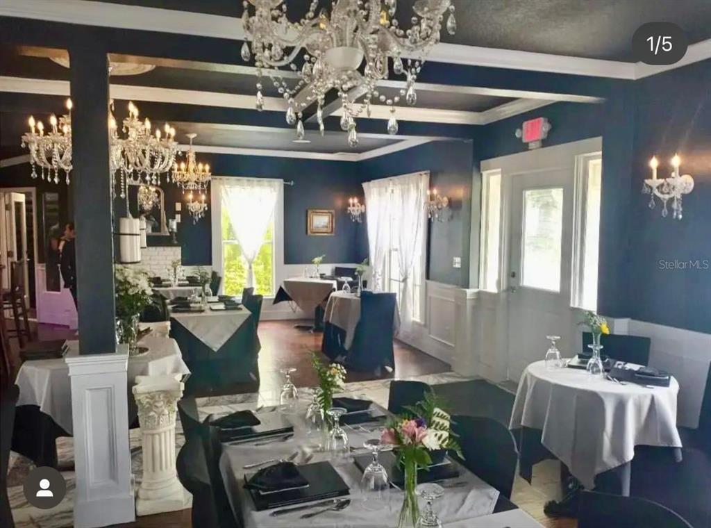 A dining room features dark blue walls, multiple crystal chandeliers, and tables with white tablecloths — 317 N ORANGE STREET, NEW SMYRNA BEACH, FL