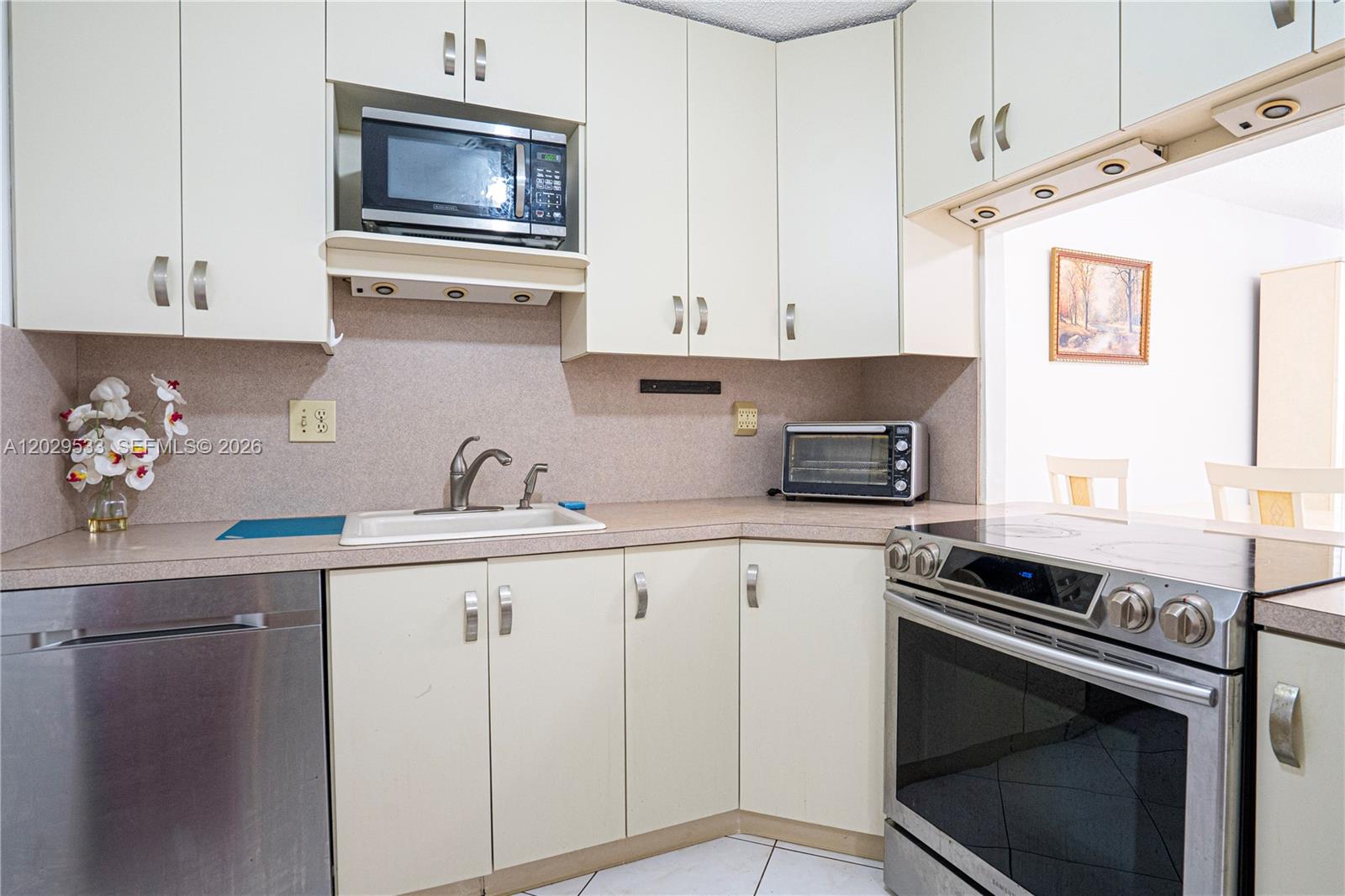 A kitchen features light-colored cabinets, stainless steel appliances, and a white sink — 600 Three Islands Blvd # 1416, Hallandale Beach FL 33009, HALLANDALE BEACH, FL