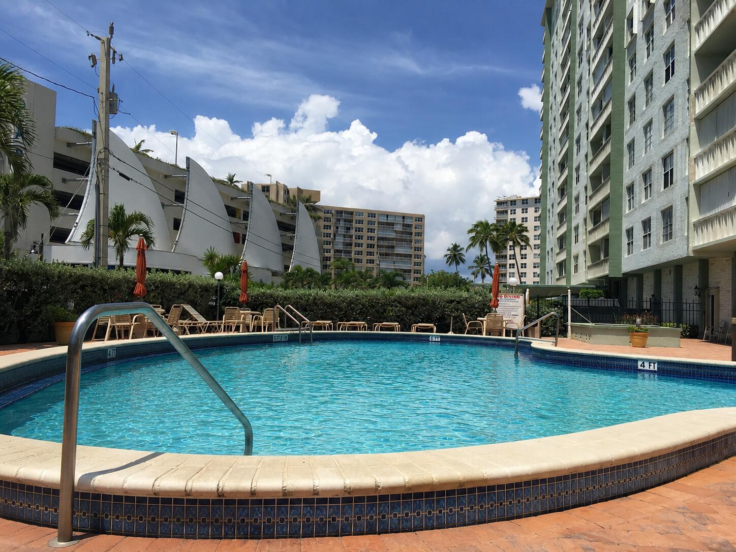 A swimming pool with a metal handrail sits in front of tall residential apartment buildings — 305 N Pompano Beach Boulevard # 606, Pompano Beach FL 33062, POMPANO BEACH, FL