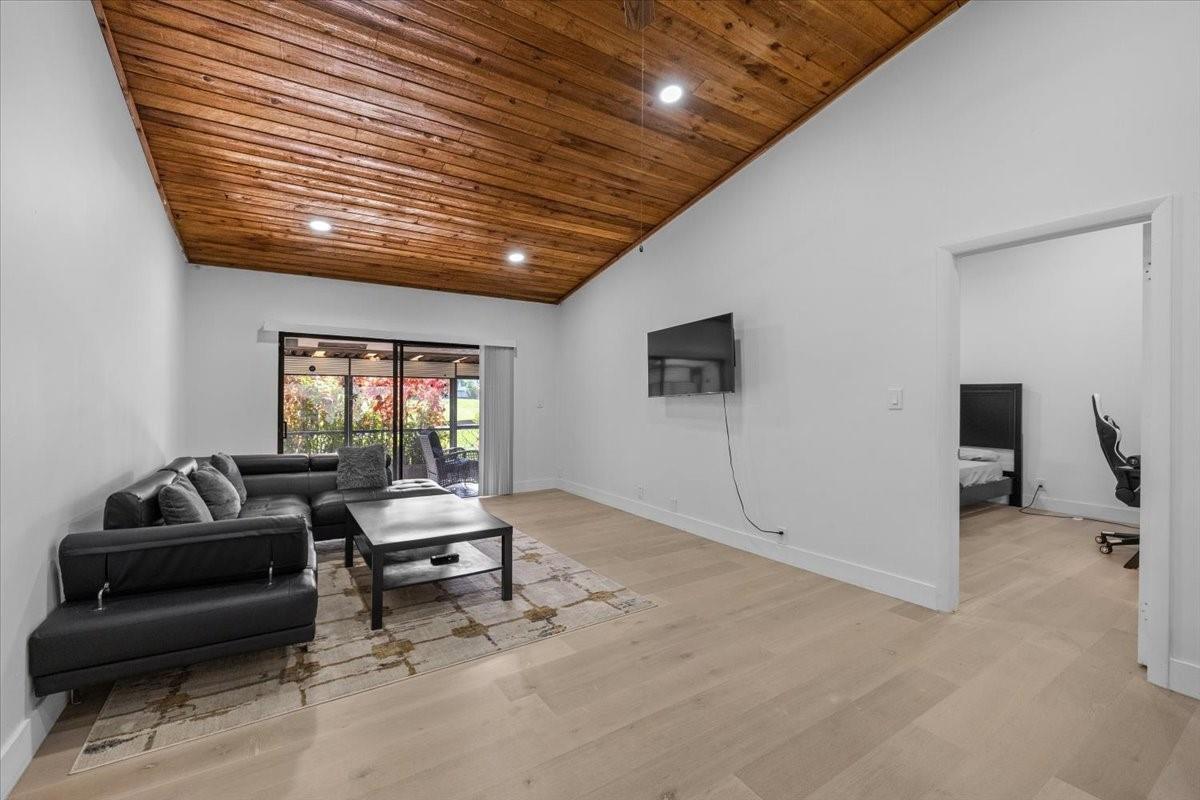 A living room features a wood-paneled vaulted ceiling, light hardwood floors, and a black sectional sofa — 8337 NW 37th Place # 8337, Sunrise FL 33351, SUNRISE, FL