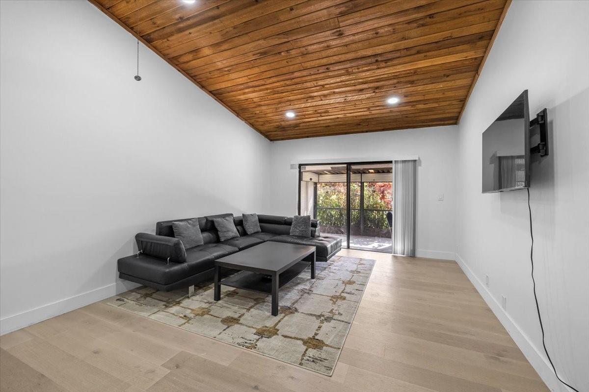 A living room features a black sectional sofa, a coffee table, and a wood-paneled ceiling — 8337 NW 37th Place # 8337, Sunrise FL 33351, SUNRISE, FL