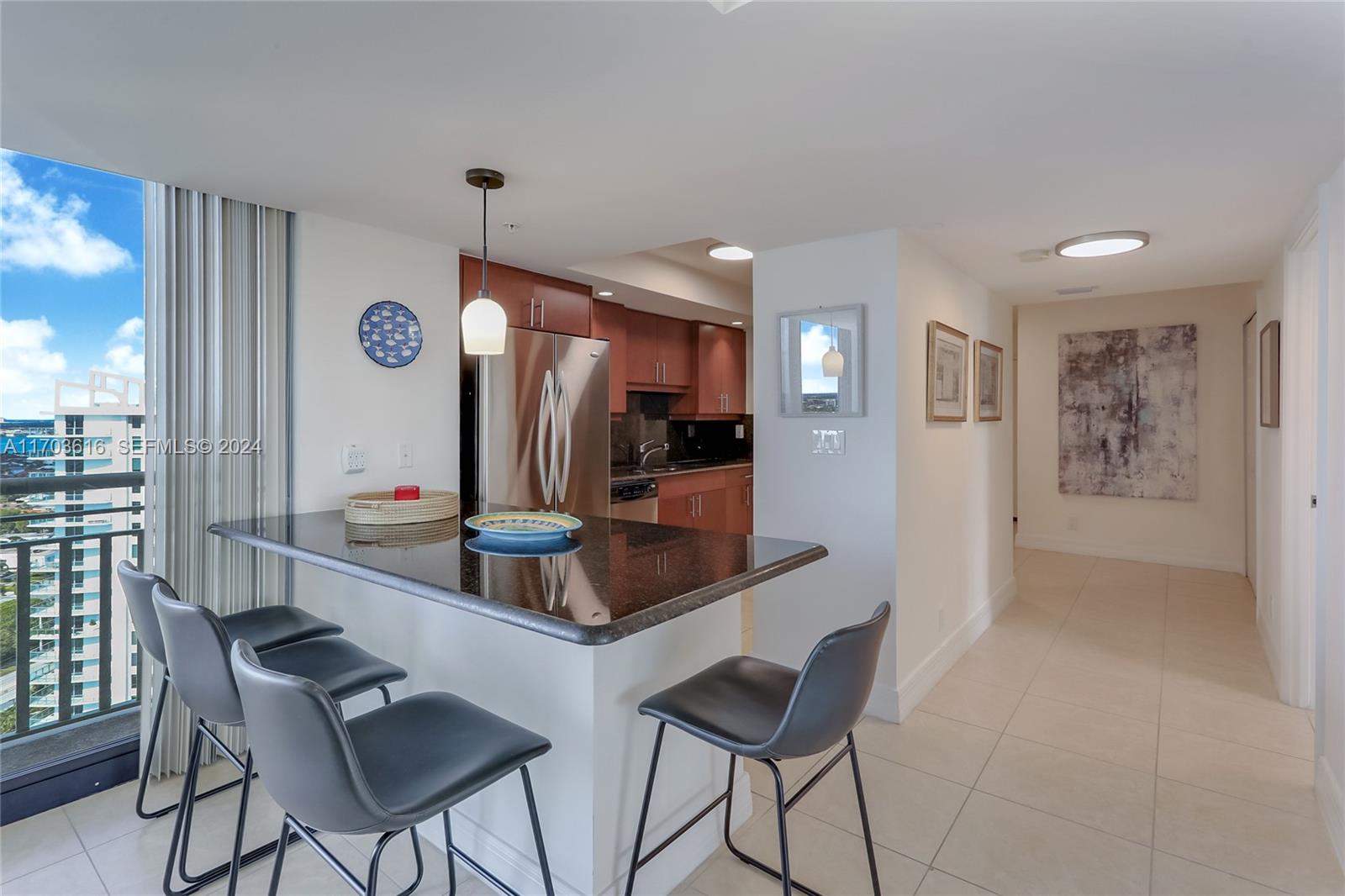 A kitchen features a black granite breakfast bar, stainless steel appliances, and a balcony view — 3000 N Ocean Dr # 24H, Riviera Beach FL 33404, RIVIERA BEACH, FL